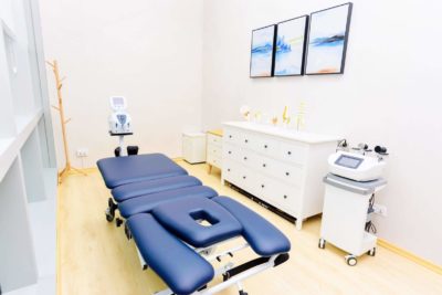 Inside Advanced Physio Care clinic, blue traction table. white room and paintings